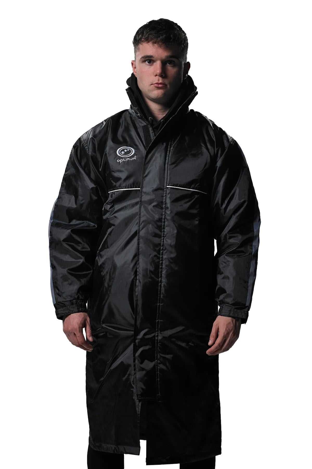 Man wearing long black Optimum sideline sub jacket, front view with white logo, on white - Optimum